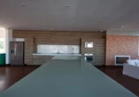 Cozinha gourmet integrada com bancada e lareira ao fundo — Condomínio Rossi Atlântida