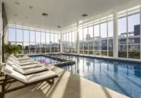 Piscina interna aquecida com espreguiçadeiras e ampla iluminação natural — Condomínio Rossi Atlântida